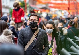 image of a street crowd with some people wearing maskes to protect against COVID-19