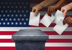 hands placing ballots in a ballot box with an American flag in the background